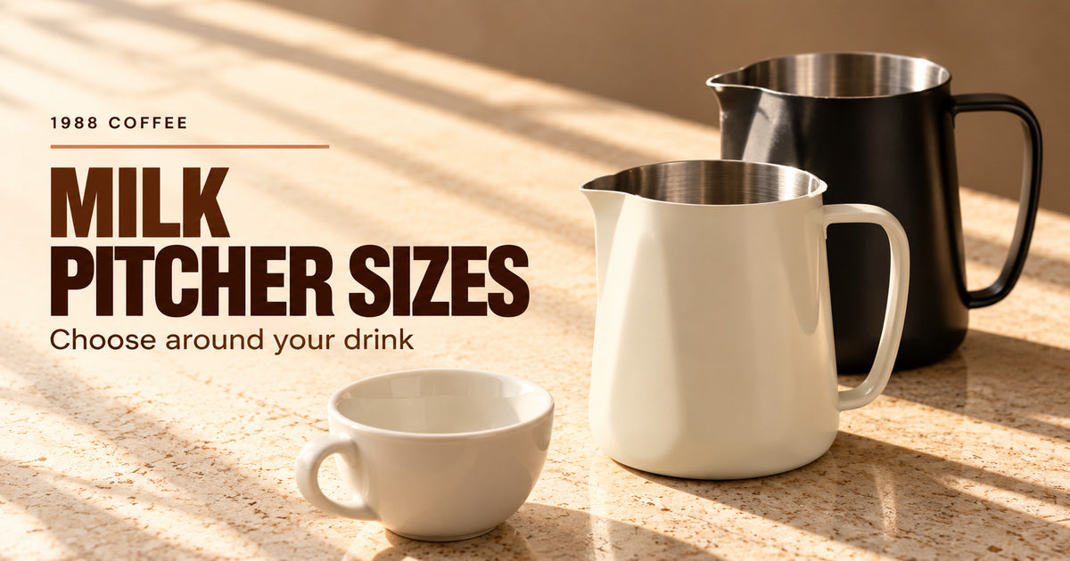 Editorial illustration of an ivory milk pitcher, a black milk pitcher and an empty cup arranged on a pale coffee counter.