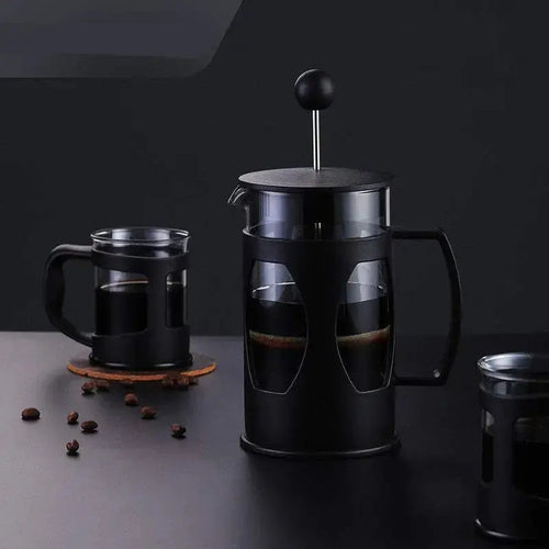 Glass French presses filled with coffee on a dark countertop
